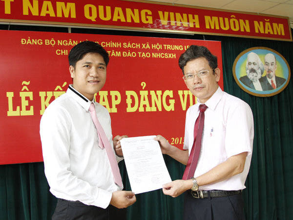 Đồng chí Trần Hữu Ý (phải) - Bí thư Chi bộ Trung tâm Đào tạo trao Quyết định kết nạp Đảng cho quần chúng ưu tú Đinh Quang Hưng