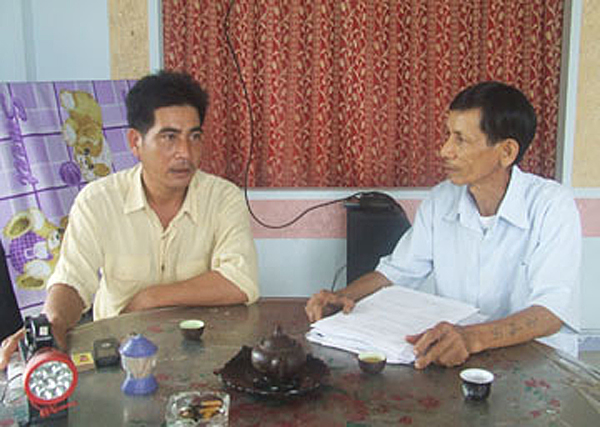 Ông Đoàn Văn Hòa (phải) trao đổi công việc vay vốn với người dân trong thôn