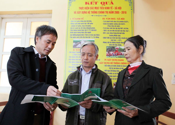 Giám đốc NHCSXH huyện Gia Viễn Lã Quốc Cường (bên trái) hướng dẫn các khách hàng vay vốn về những thông tin trong Sổ vay vốn