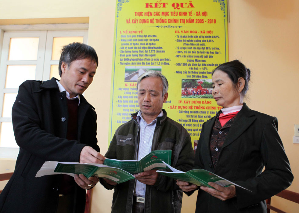 Giám đốc NHCSXH huyện Gia Viễn Lã Quốc Cường (bên trái) hướng dẫn các khách hàng vay vốn về những thông tin trong Sổ vay vốn