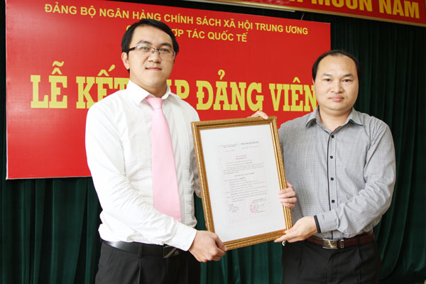 Đồng chí Phan Cử Nhân (phải) - Bí thư Chi bộ Hợp tác quốc tế trao Quyết định cho đảng viên mới Phan Anh