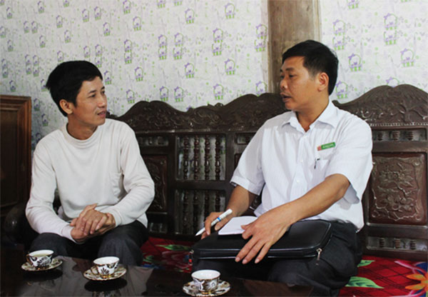 Anh Ma Đình Thủy (trái) đang trao đổi với cán bộ NHCSXH huyện về kế hoạch trả nợ của gia đình