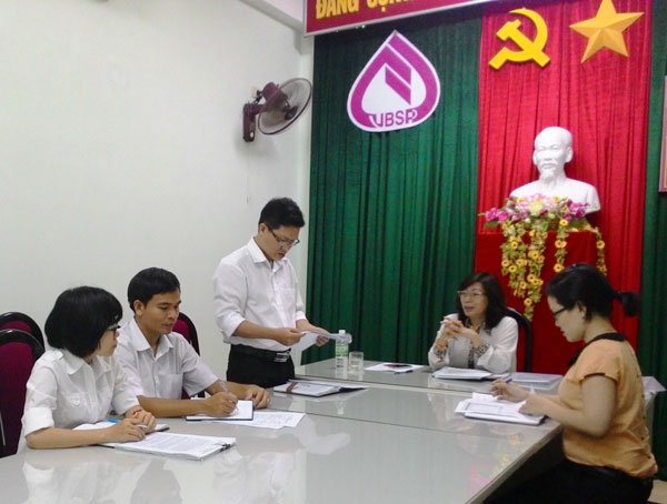 Bùi Nhật Quang (người đứng) đang trao đổi nghiệp vụ với các đồng nghiệp