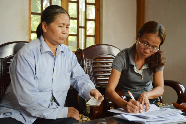 Tổ trưởng Trần Thị Sâm (phải) đang nhận tiền gửi tiết kiệm của tổ viên