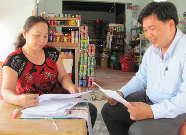 Chị Nguyễn Hồng Anh cùng cán bộ tín dụng NHCSXH đang trao đổi công tác quản lý tín dụng trên địa bàn