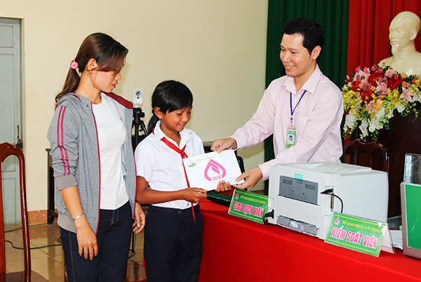 Cán bộ NHCSXH tỉnh Đắk Lắk làm thủ tục trao tiền ủng hộ của các nhà hảo tâm cho người giám hộ và em nhỏ có hoàn cảnh khó khăn
