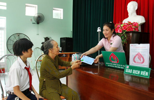 Cán bộ NHCSXH tỉnh Bình Định làm thủ tục trao tiền ủng hộ của các nhà hảo tâm cho bà Hà Thị Mây - người giám hộ của em Võ Viết Thắng
