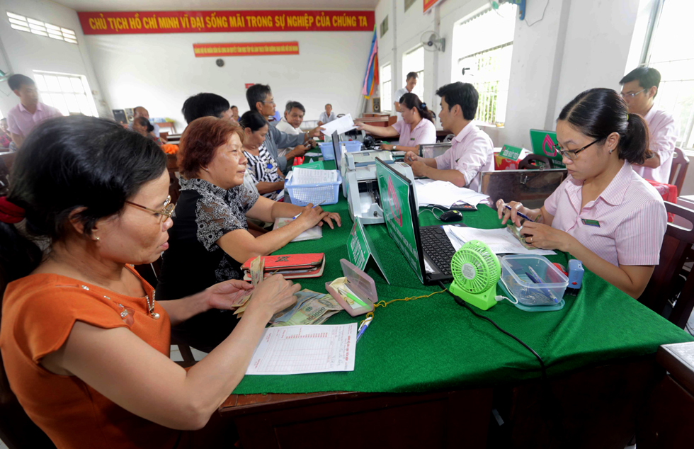 Người nghèo trên địa bàn xã Bình Phước Hòa, huyện Long Hồ làm thủ tục nhận tiền vay tại Điểm giao dịch xã của NHCSXH