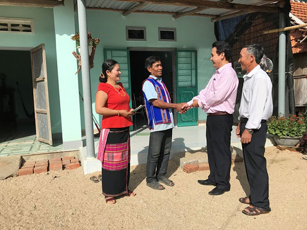 Vợ chồng ông Trần Văn Miên và bà Đinh Thị A Lơi đón cán bộ NHCSXH, Tổ trưởng đến thăm ngôi nhà mới