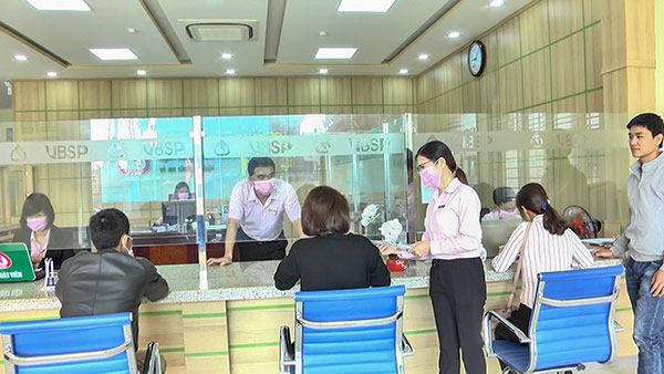 Cán bộ của NHCSXH huyện Vĩnh Linh cấp phát miễn phí khẩu trang y tế cho khách hàng