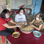 Em Nguyễn Thái Kim Anh ( áo trắng) giúp mẹ cạo vỏ hạt điều