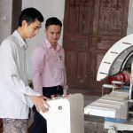 Anh Phan Văn Kiều giới thiệu máy làm khung nhôm kính với cán bộ NHCSXH huyện Đô Lương