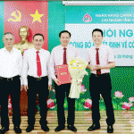 Phó Tổng Giám đốc NHCSXH Hoàng Minh Tế và Lãnh đạo tỉnh Đồng Nai trao Quyết định, tặng hoa chúc mừng ông Lê Bá Chuyên