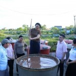 Vợ chồng ông Dương Hà Nam - chủ cơ sở sản xuất nước mắm truyền thống ở Nghĩa Nam (người đứng ngoài cùng bên trái và đứng giữa) giới thiệu sản phẩm mắm nêm truyền thống với cán bộ NHCSXH